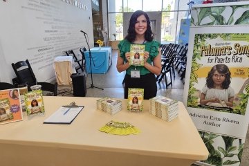 Mercy University employee Adriana Erin Rivera poses with her book Paloma’s Song for Puerto Rico: A Diary from 1898 