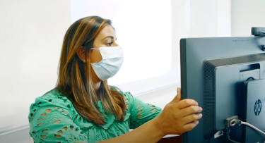 Woman in mask at computer