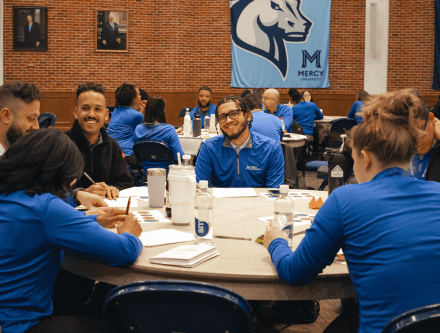 Teams of counselors in blue shirts at tables